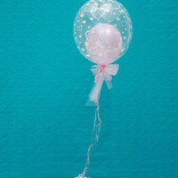 kleiner rosa Ballon in einem größeren durchsichtigen Ballon mit rosa Schleife